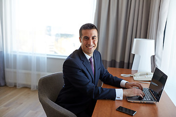 Image showing businessman typing on laptop at hotel room