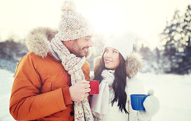 Image showing happy couple with tea cups over winter landscape