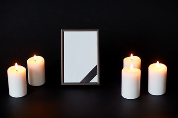 Image showing black ribbon on photo frame and candles at funeral