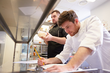 Image showing chef and cook with lists or bills at kitchen