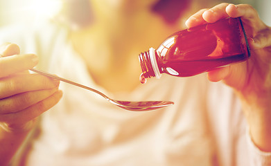 Image showing woman pouring medication from bottle to spoon