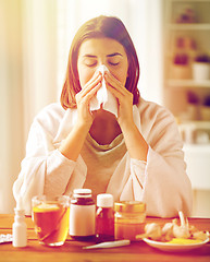 Image showing sick woman with medicine blowing nose to wipe