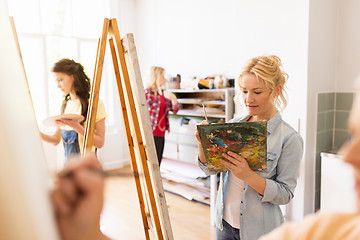 Image showing woman artist with easel painting at art school