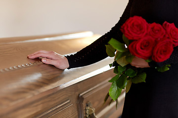 Image showing woman with red roses and coffin at funeral