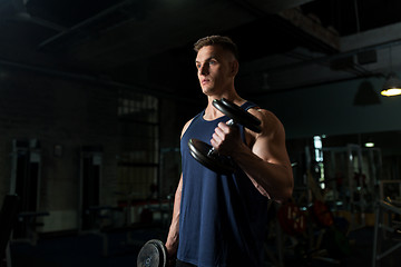 Image showing young man with dumbbells exercising in gym