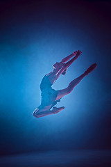 Image showing Beautiful young ballet dancer jumping on a lilac background.