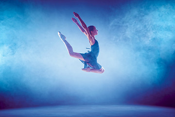 Image showing Beautiful young ballet dancer jumping on a lilac background.