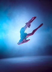 Image showing Beautiful young ballet dancer jumping on a lilac background.