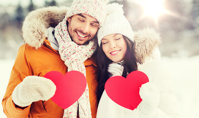 Image showing happy couple with red hearts over winter landscape