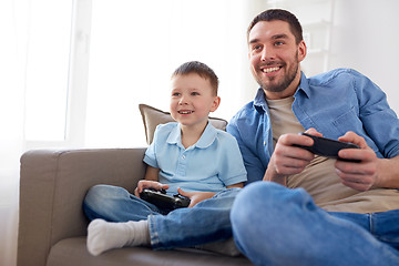 Image showing father and son playing video game at home