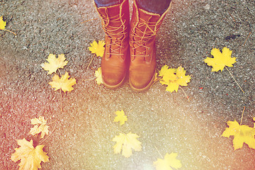 Image showing female feet in boots and autumn leaves