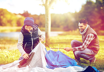 Image showing happy father and son setting up tent outdoors