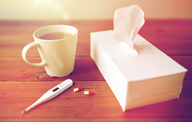 Image showing cup of tea, paper wipes and thermometer with pills