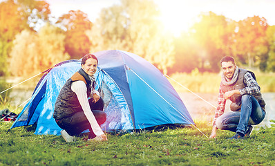 Image showing happy couple setting up tent outdoors