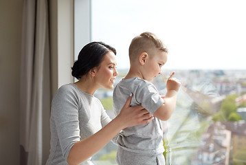 Image showing mother and son looking through window at home