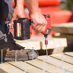 Image showing Carpenter working with an electric screwdriver.