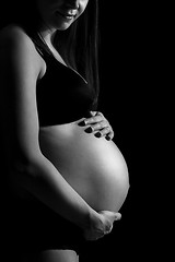 Image showing Pregnant woman caressing her belly isolated on black monochrome background.