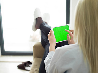 Image showing young woman using tablet computer in front of fireplace