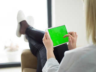 Image showing young woman using tablet computer in front of fireplace