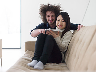 Image showing multiethnic couple at home using tablet computers