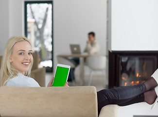 Image showing young woman using tablet computer in front of fireplace