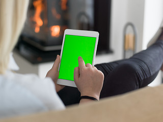 Image showing young woman using tablet computer in front of fireplace