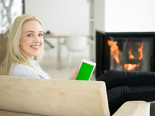 Image showing young woman using tablet computer in front of fireplace