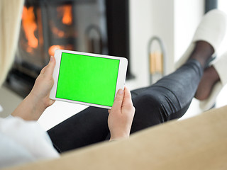 Image showing young woman using tablet computer in front of fireplace