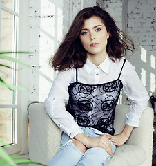 Image showing young pretty brunette woman in her bedroom sitting at window, happy smiling lifestyle people concept