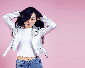 Image showing young pretty smiling asian korean girl wearing modern fashion clothers on pink background, lifestyle people concept 