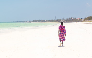 Image showing Maasai warrior walking on picture perfect tropical sandy beach. Paje, Zanzibar, Tanzania.