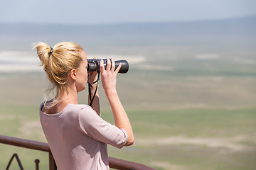 Image showing Female tourist looking through binoculars on African safari in Ngorongoro crater consrvation area, Tanzania, Afrika.