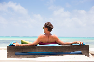 Image showing Relaxed man in luxury lounger enjoying summer vacations on beautiful beach.