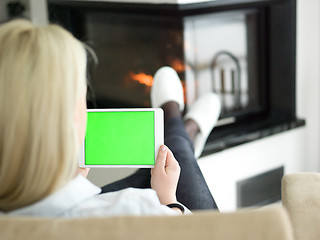 Image showing young woman using tablet computer in front of fireplace