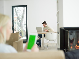 Image showing young woman using tablet computer in front of fireplace