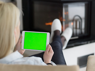 Image showing young woman using tablet computer in front of fireplace