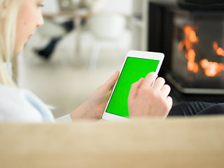 Image showing young woman using tablet computer in front of fireplace