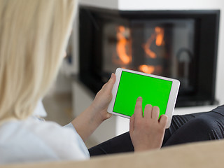 Image showing young woman using tablet computer in front of fireplace