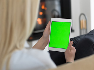 Image showing young woman using tablet computer in front of fireplace