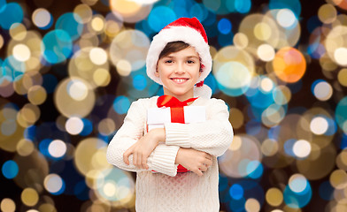 Image showing smiling happy boy in santa hat with christmas gift