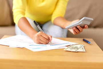 Image showing woman with money, papers and calculator at home