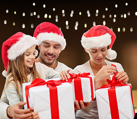 Image showing happy family in santa hats with christmas gifts