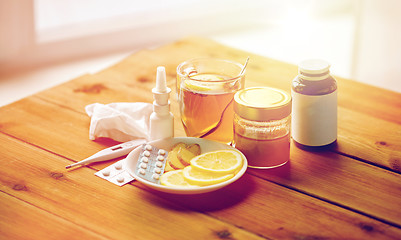 Image showing drugs, thermometer, honey and cup of tea on wood