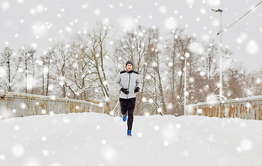 Image showing man running along snow covered winter bridge road