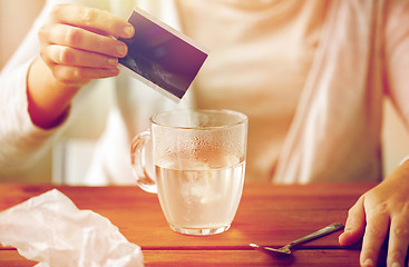 Image showing woman pouring medication into cup of water