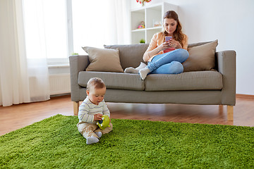 Image showing mother with smartphone and baby playing at home