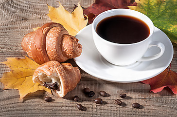 Image showing Coffee with a croissant on a wooden table