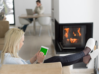 Image showing young woman using tablet computer in front of fireplace