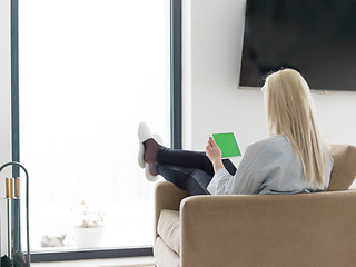 Image showing young woman using tablet computer in front of fireplace