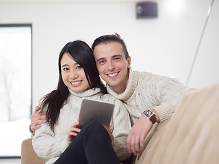 Image showing multiethnic couple at home using tablet computers